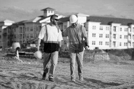 Téléchargez les photos : Travailleurs de la construction travaillant sur le chantier. Hommes portant des gilets de sécurité et des casques de construction. Contremaître et constructeur de construction. - en image libre de droit