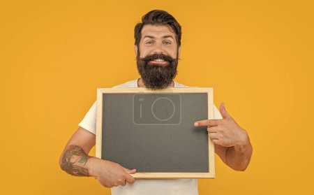 Foto von Mann Angebot Werbung zeigt auf Tafel isoliert auf gelbem Hintergrund mit Kopierraum.