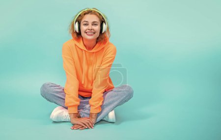 woman has music lifestyle on background, copy space. photo of woman has music lifestyle wear headphones. woman has music lifestyle isolated on blue. woman has music lifestyle in studio.
