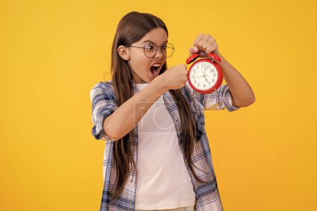 punctuality in early morning time. school time schedule. teen girl with alarm clock. Time ticking for a busy teen girl. teen girl check time at the clock while studying. Teen girl has deadline.