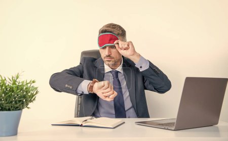 tired boss check time in sleep mask at workplace.