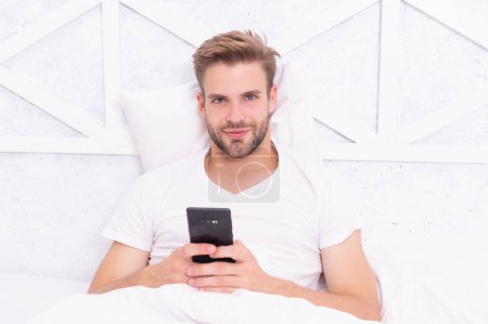Man read message in bedroom. Browsing social media. Online shopping. Millennial man use smartphone in bed at home. Man chat on smartphone. Message chatting online. Morning chat. Internet addiction.