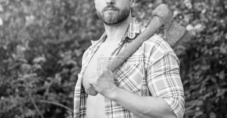 cropped view of rancher with axe outdoor. photo of rancher with axe. rancher with axe. rancher with axe wearing checkered shirt.