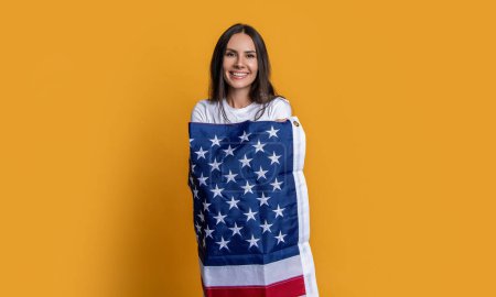 Patriotism personified. woman with American flag. Symbol of strength and freedom. woman wrapped in the American flag. American roots. woman with the flag. A woman proudly holding the American flag.