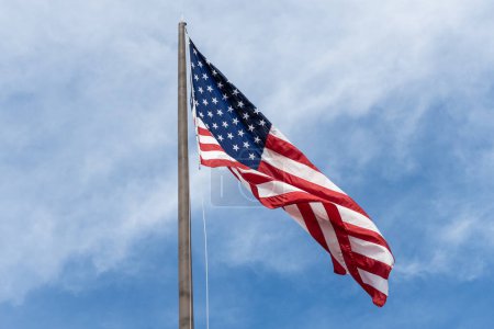 American flag waving in the wind. Flag of the USA. National waving flag of united states on sky. Independence day. Patriotic symbol. American Flag for Memorial Day or 4th of July. Display patriotism.