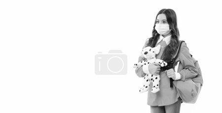 school girl in mask with toy at studio. school quarantine. photo of girl in quarantine mask. school girl in medical mask with copy space. school girl in mask on quarantine isolated on white background