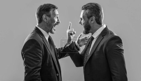 arguing businessmen shouting. photo of businessmen arguing with anger. two arguing businessmen isolated on grey background. businessmen arguing in studio.