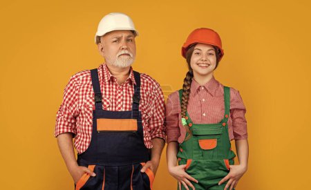 happy child and granddad builder in helmet on yellow background. labor day.