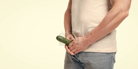 Man crop view holding cucumber at crotch level imitating penis isolated on white, copy space.