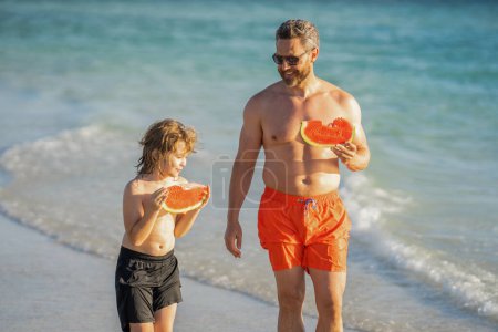 dad and kid son at fathers day during summer holiday and vacation enjoing fatherhood and childhood while eating watermelon at sea.