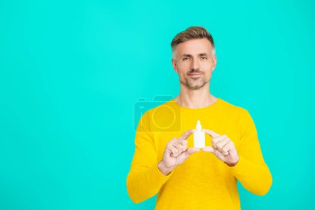 Man offering a nasal spray. Nasal irrigation. Treatment of a runny nose. Rhinitis. Medicine and health care. Medical spray or drops. Man with nasal or eyecare medication. Copy space.