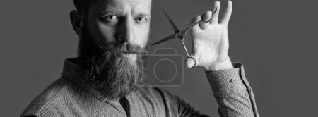 hairdresser man with scissors to make haircut. man in hairdresser studio. man holding hairdresser scissors for haircut. concept of mens haircut. man hairdresser do haircut isolated on grey background.