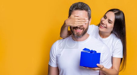 Loving woman giving present for Valentines day. Gift box to surprised man. Boyfriend receiving present from girlfriend. Valentines day couple. Couple in love. Mans day gift. Copy space.