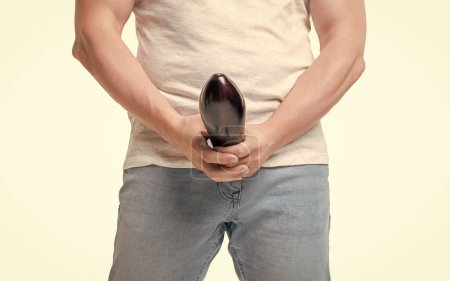 Man crop view holding eggplant at crotch level imitating large penis isolated on white.