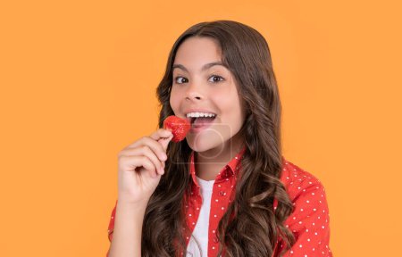 smiling teen girl eat strawberry on yellow background.