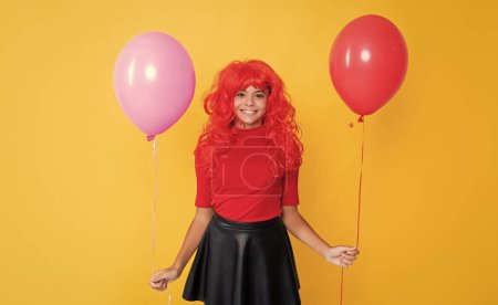 glad girl with party balloon on yellow background.
