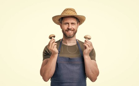 hombre feliz en delantal y sombrero con seta vegetal aislado en blanco.