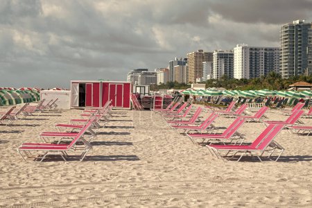 Chaiselongen in miami, USA. rosa Chaiselongen am Strand hintereinander. Strandmöbel. Urlaub am Meer. Sommerferien.