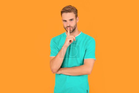 portrait of man with bristle in blue shirt. young man keep secret on yellow background. hair and beard care. confident and handsome unshaven guy. male casual fashion. mens beauty.
