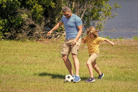 dad and son enjoying childhood adventures outdoor. dad and son playing football during their childhood. Childhood memories of son and his dad. dad have fun with his son. outdoor experiences.