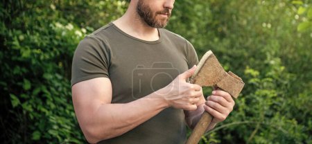 man with ax outdoor. cropped photo of man with ax. man with ax. man with ax wearing shirt.
