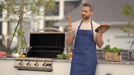 photo of chef with grilled salmon, copy space banner. chef with grilled salmon. chef man cooking grilled salmon outdoor. grilled salmon fish at man wear chef apron.