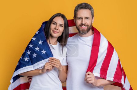 glückliches amerikanisches Familienpaar mit Fahne. Ein Paar posiert stolz mit der amerikanischen Flagge. Patriotismus des Paares mit der amerikanischen Flagge. Feier des amerikanischen Spirituosenpaares in der Fahne drapiert.