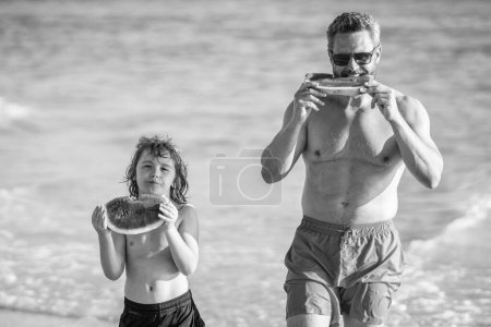 father dad and son childhood on summertime vacation. single father with son childhood at the beach. Loving dad father and son enjoying quality time together at sea. Father and son eating watermelon.