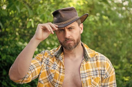 Mann mit Cowboyhut. sexy Mann trägt kariertes Hemd. Westlicher Mann mit Hut.