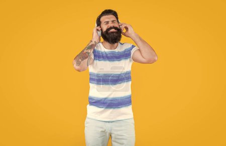 listen to music. modern device of happy man. hipster man listen music in earphones isolated on yellow background. man in hipster earphones listen music. studio shot of hipster man with earphones.