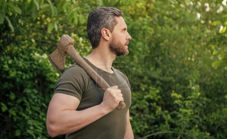 man hold axe wearing shirt. man with axe outdoor. photo of man with axe. man with axe.