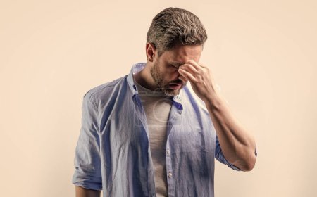 man with headache or migraine isolated on grey. mature man with headache and migraine in studio. photo of man with migraine headache. man with headache or migraine wear shirt.