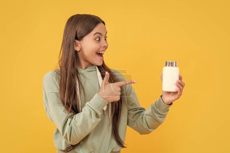 teen girl pointing finger on medication isolated on yellow. teen girl with medication in studio. teen girl with medication on background. photo of teen girl with medication pill.