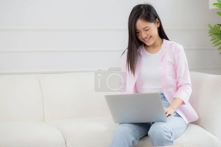 Young asian business woman work from home with laptop computer online to internet on sofa in living room, freelance girl using notebook sitting on couch with comfort and relax, lifestyles concept. Poster 659072312
