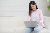 Young asian business woman work from home with laptop computer online to internet on sofa in living room, freelance girl using notebook sitting on couch with comfort and relax, lifestyles concept. Poster #659072312