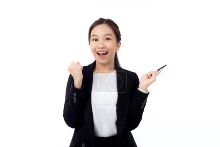 A cheerful young asian businesswoman in a suit, smiling and looking up, holding a pen, celebrating a success isolated white background, joyful business woman with pen celebrating success.