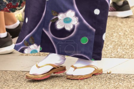 Foto de Detalle de los pies de una chica japonesa con kimono florecido azul y calzado tradicional japonés con zuecos y calcetines tradicionales - Imagen libre de derechos