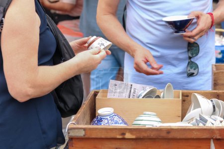 Frau kauft Keramik auf Flohmarkt
