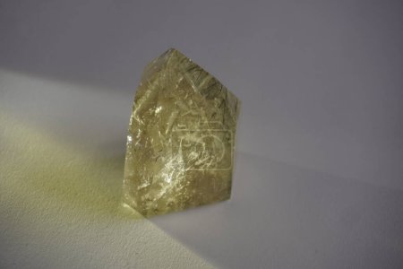 Rutilated quartz crystal in golden tones with reflection on white background