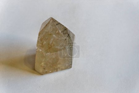 Rutiliertes Quarzkristall in goldenen Tönen mit Reflexion auf weißem Hintergrund
