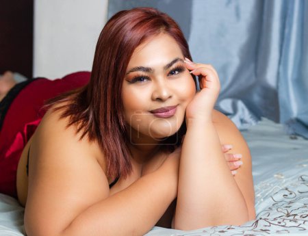 Téléchargez les photos : Sensuelle femme latine plus la taille allongée sur le lit. modèle de surcharge pondérale - en image libre de droit