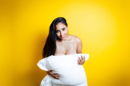 Foto de Mujer hispana desnuda sensual cubriendo su cuerpo con almohada - Imagen libre de derechos