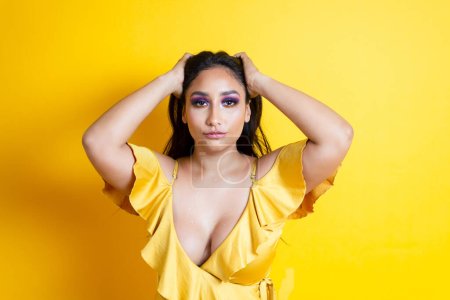 Photo for Portrait of elegant and sensual hispanic young woman holding her hair in yellow dress - Royalty Free Image