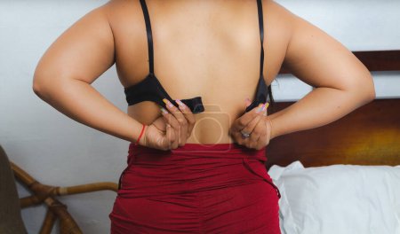 Foto de Mujer de detrás desabrochándose y quitándose el sostén. mujer latina desnudándose - Imagen libre de derechos