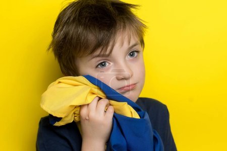 Photo for Little Ukrainian boy hugs the flag of his country - Royalty Free Image