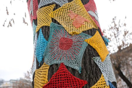 Foto de Knitted patterns on a tree on the street. decoration or decor - Imagen libre de derechos