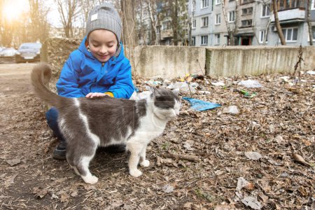Photo for A little boy strokes a cat on the street. soft focus homeless animals - Royalty Free Image