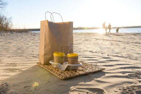 Foto de Vasos de papel kraft y bolsa de papel en la playa. eco amigable - Imagen libre de derechos