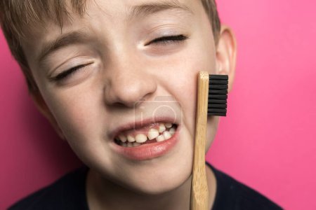 Téléchargez les photos : Un petit garçon tient une brosse à dents en bambou dans ses mains. respectueux de l'environnement - en image libre de droit