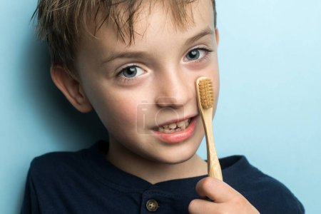 Téléchargez les photos : Un garçon d'apparence européenne tient une brosse à dents en bambou dans ses mains - en image libre de droit